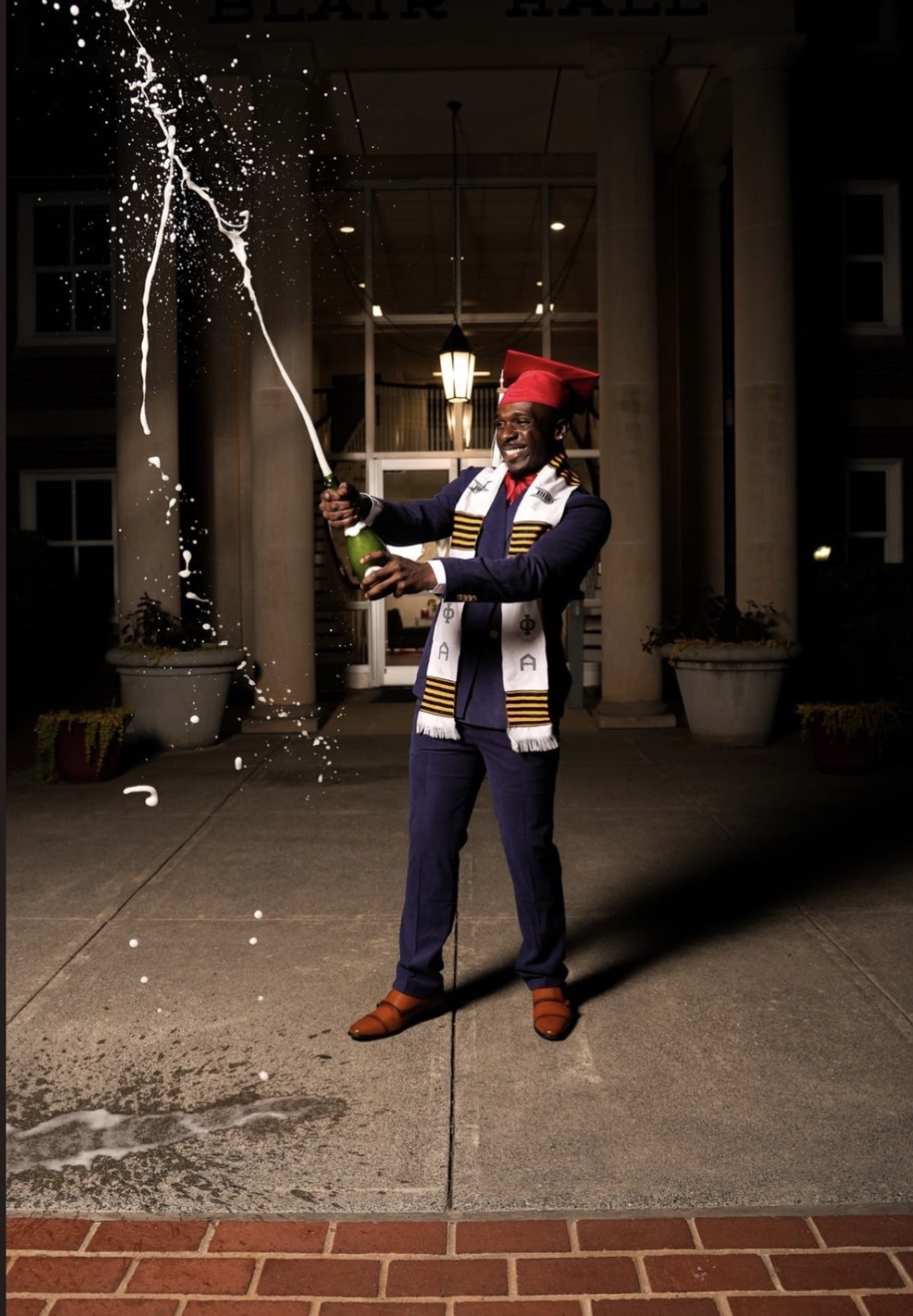 Graduate celebrating with a champagne splash outside Blair Hall